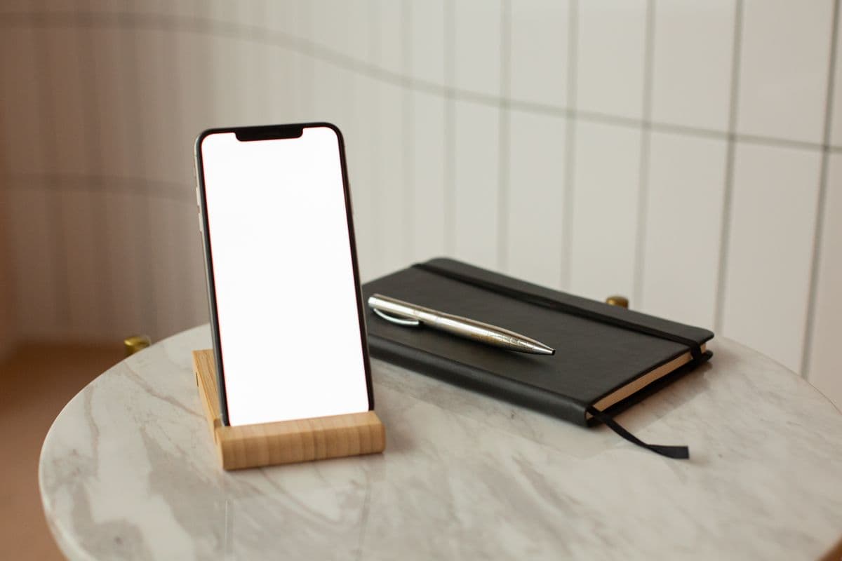 Ein Smartphone ohne sichtbare Inhalte neben einem Notizbuch.
