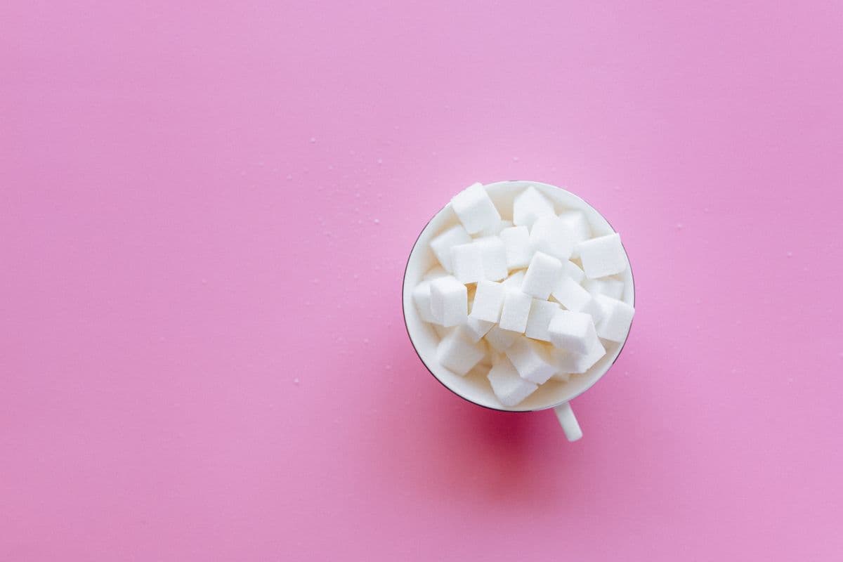 Eine Tasse mit Zuckerwürfeln als Symbol für zugesetzten Zucker.